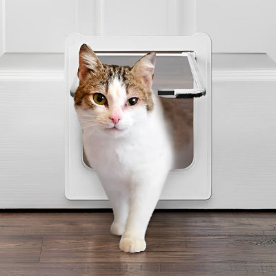 Chat tacheté sortant d'une chatière pour chat installée sur une porte blanche.
