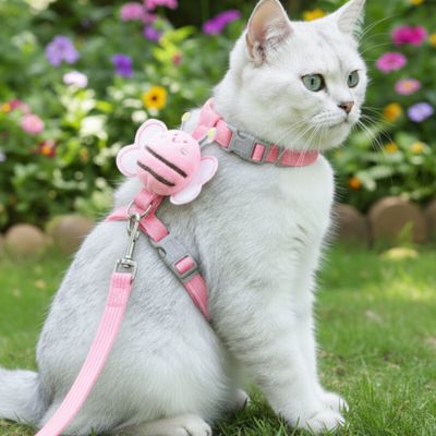 Chats blanc avec harnais pour chat rose en forme d abeille dans un jardin