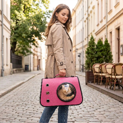 Sac pour transporter chat rose fuchsia à hublot tenu à la main.