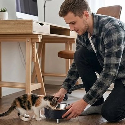 Homme présentant une gamelle chat surélevée noire à son chat